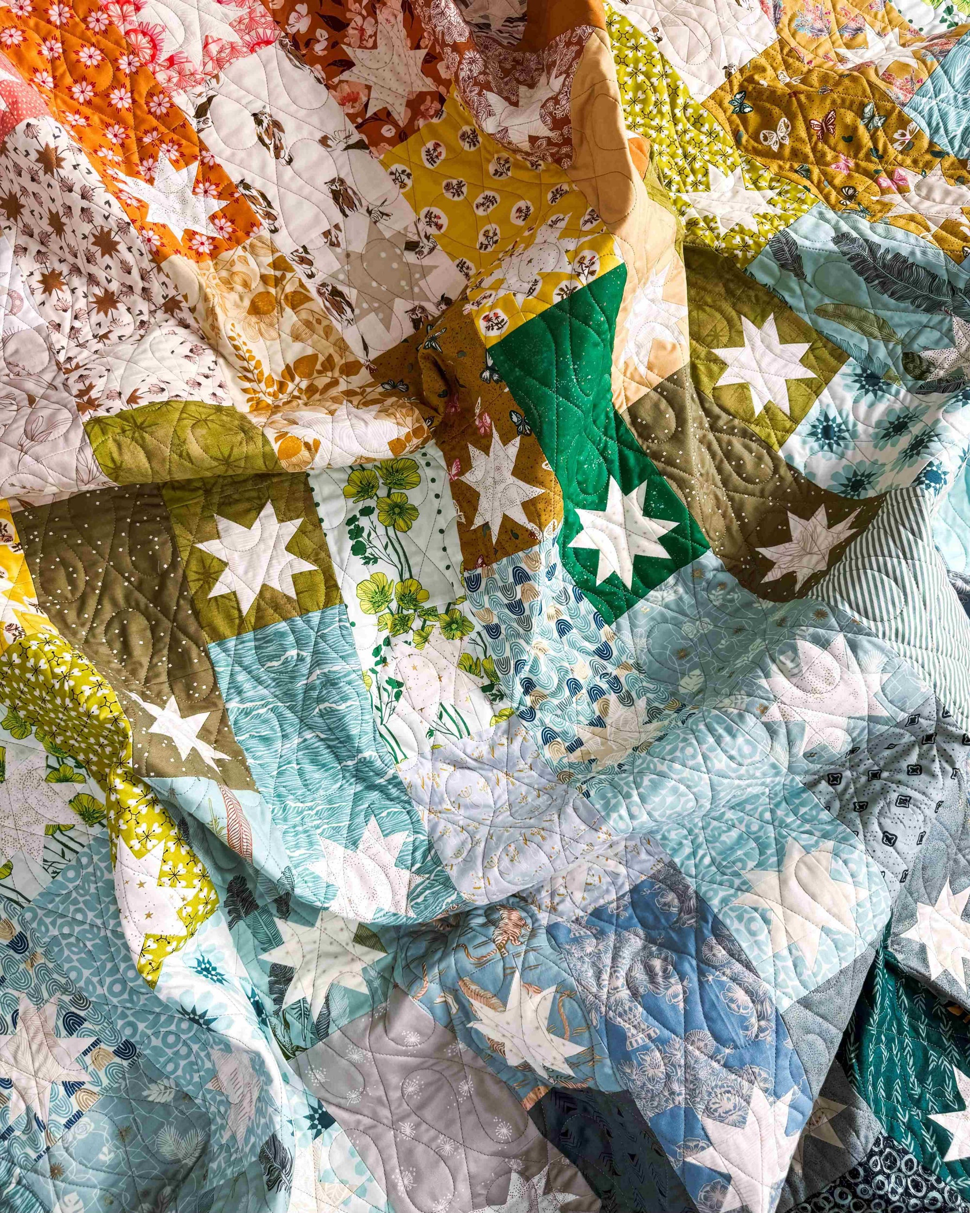 rainbow patchwork quilt with star designs, casually rumpled