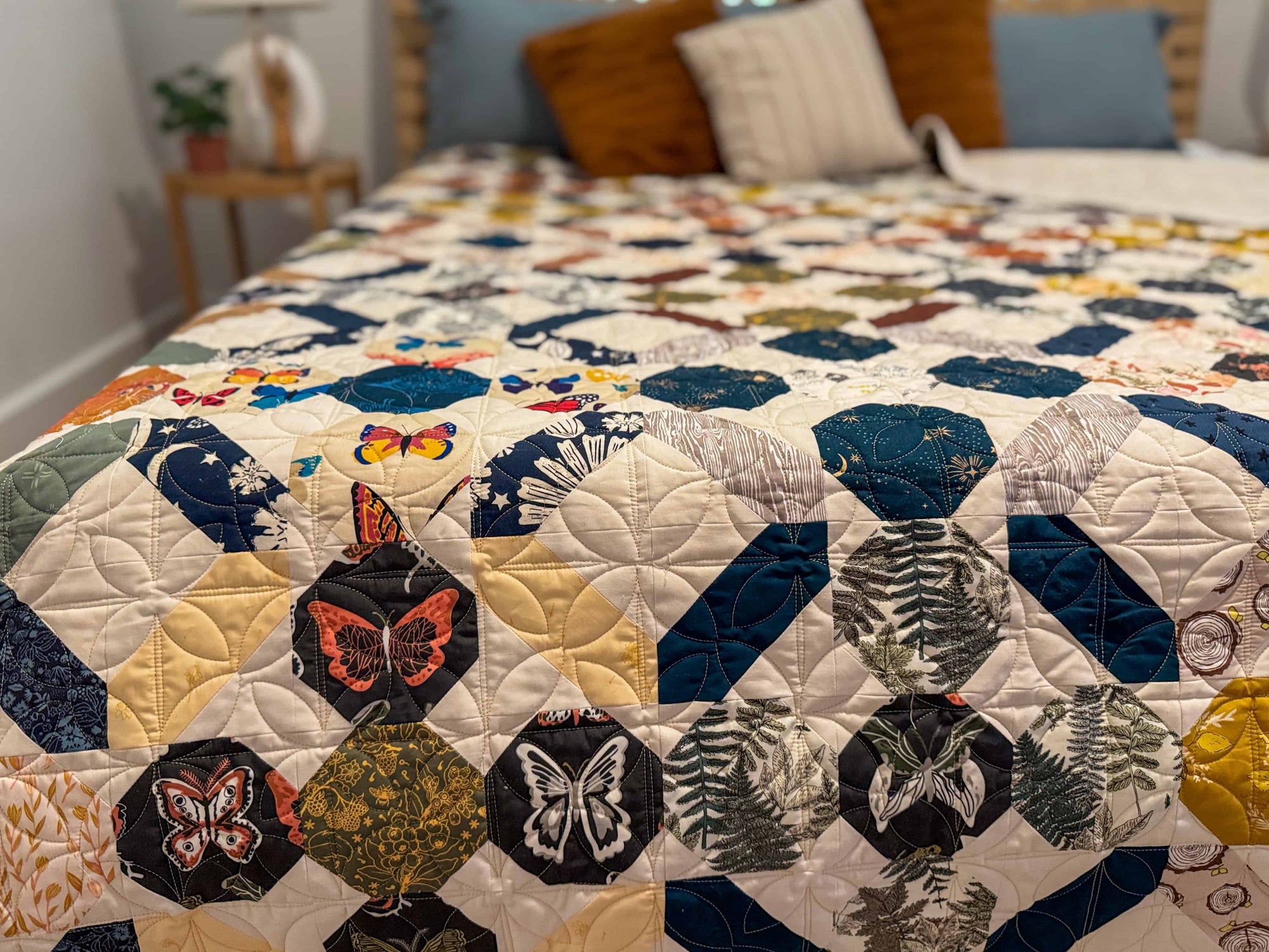 patchwork quilt with butterfly print fabrics in rounded blocks and shades of navy, gold, brown, and sage green