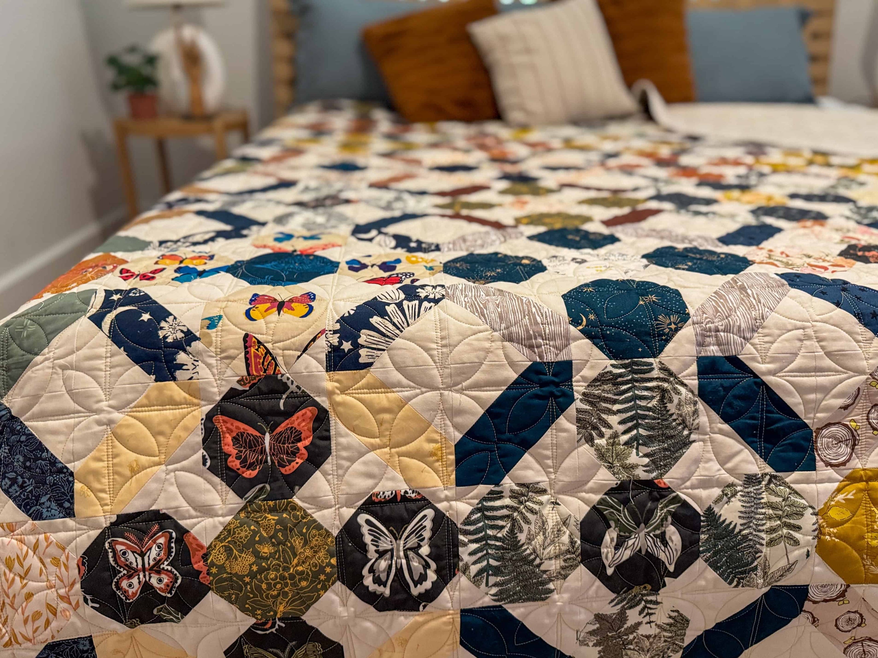 patchwork quilt with butterfly print fabrics in rounded blocks and shades of navy, gold, brown, and sage green