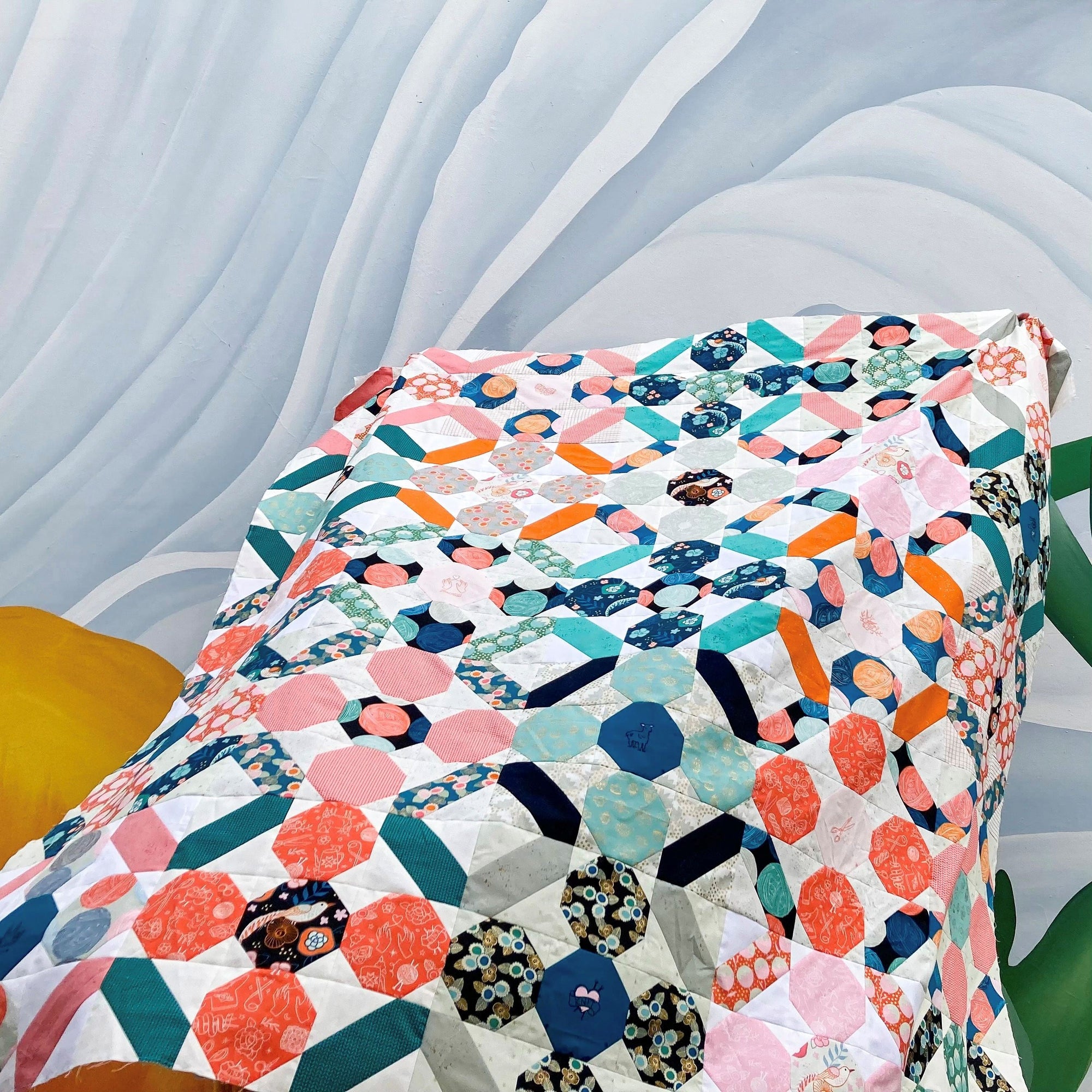 picture of a patchwork quilt made from Knuffel quilt pattern blowing in breeze in front of large flower mural