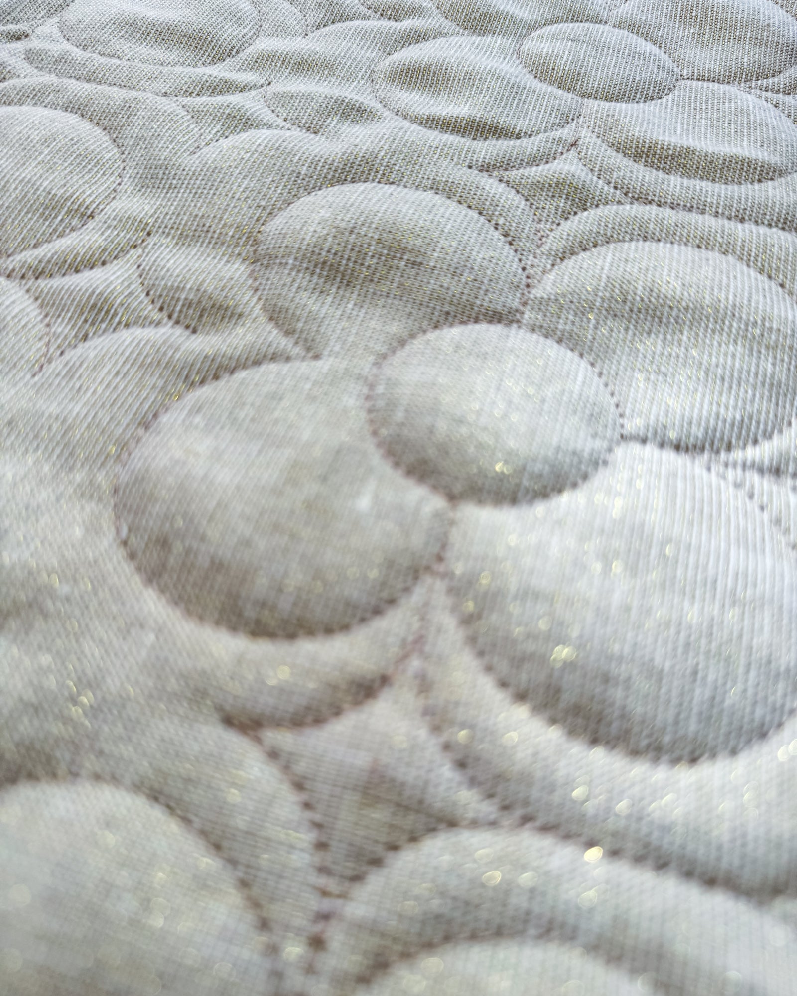 Close-up of a textured fabric with circular patterns and metallic gold flecks