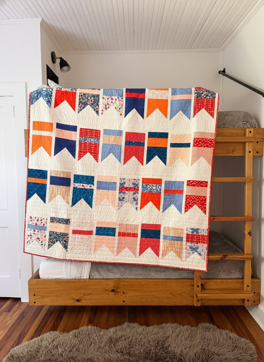 Red, orange, white and blue quilt with geometric bunting pattern draped over a wooden ladder in a room.